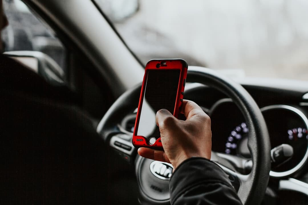Person holding phone while sitting behind the wheel of a car