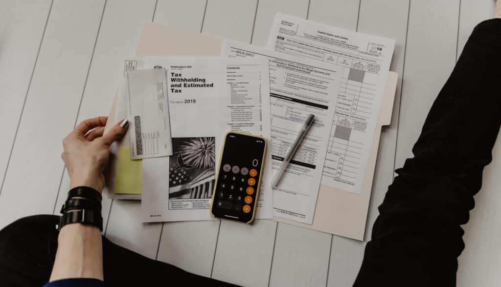 A person reviewing financial paperwork with a calculator